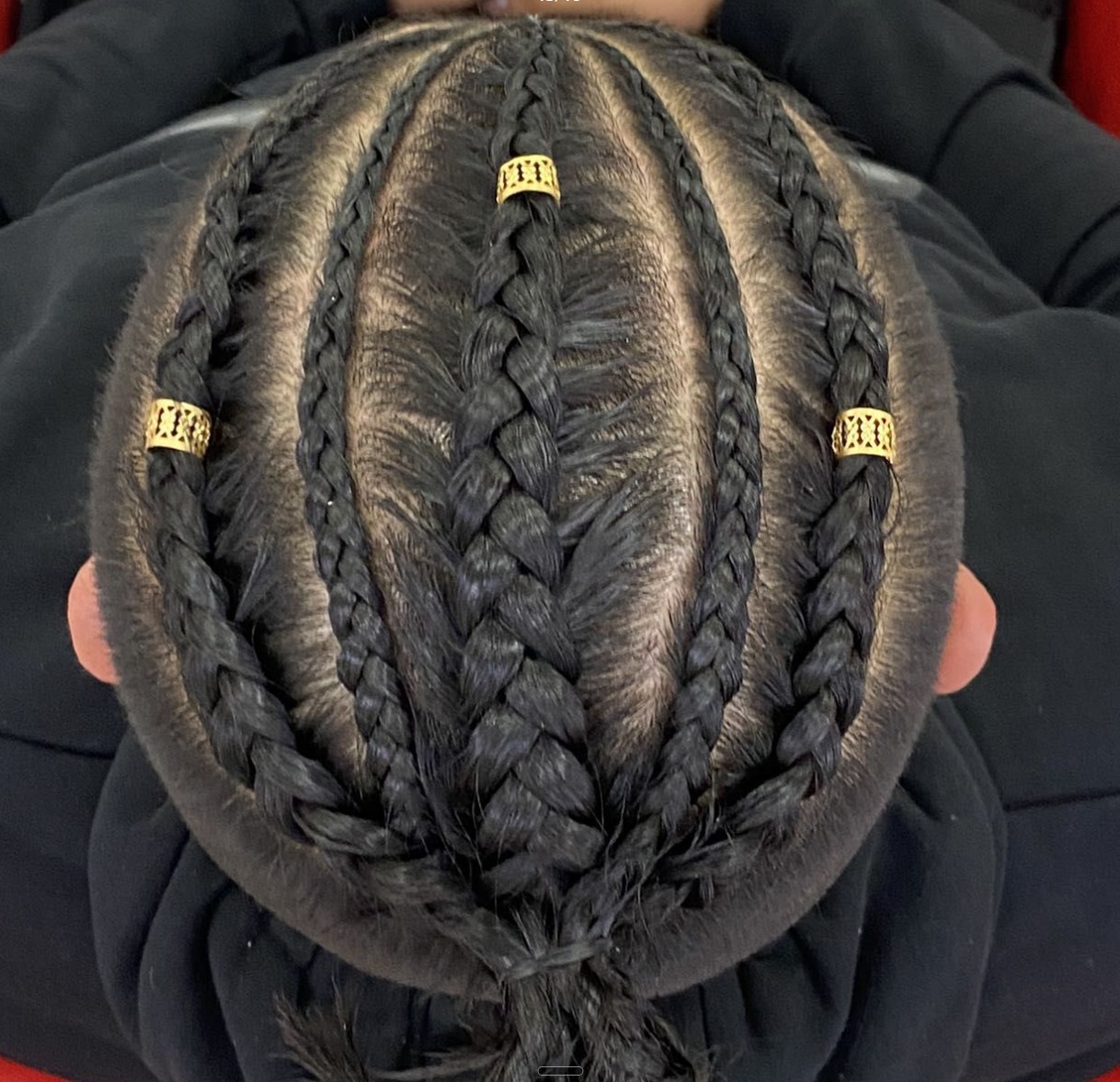 Top down view of neat cornrow braids finished with gold cuffs