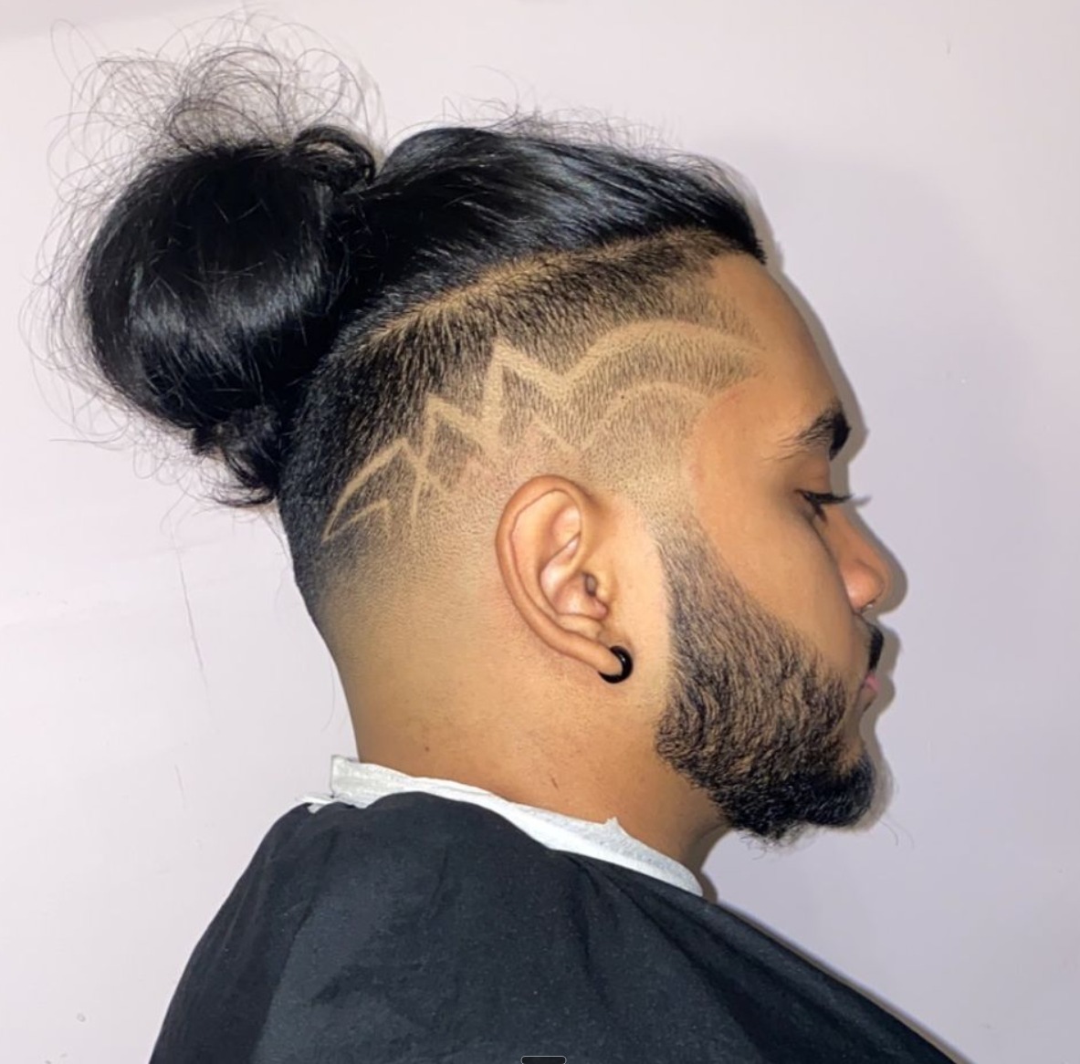 Man bun with a skin fade and a lightning style design cut into the side