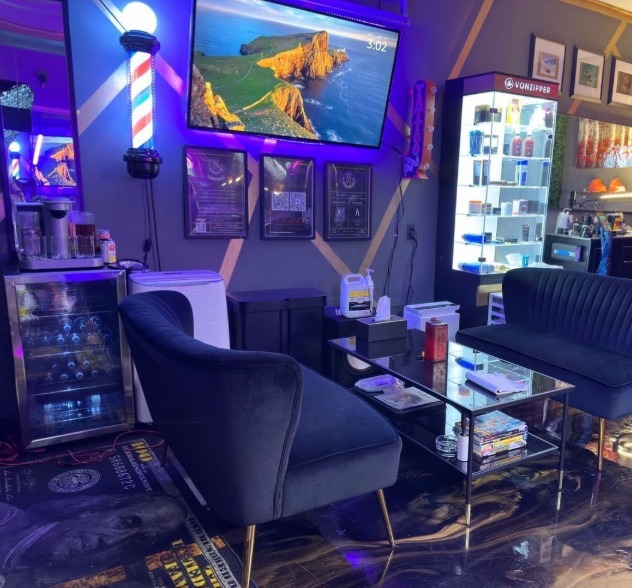 The lounge with a barber pole, velvet chairs, a glass table and a drinks fridge