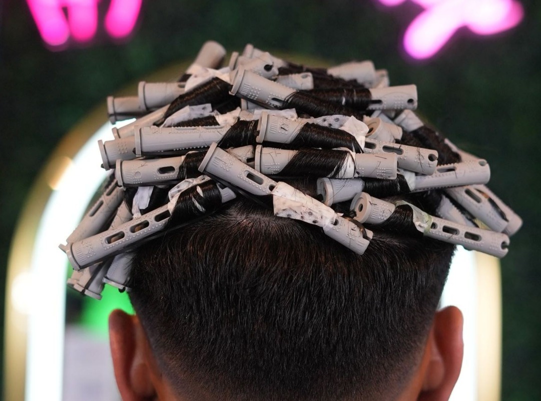 Grey perm rods wrapped section by section across the top of the head