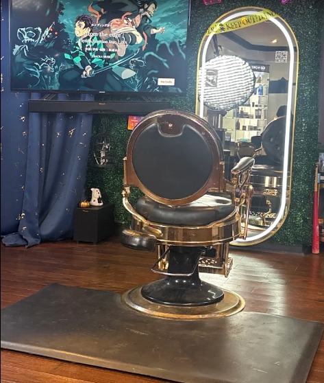 The gold barber chair beside an oval mirror and a green wall